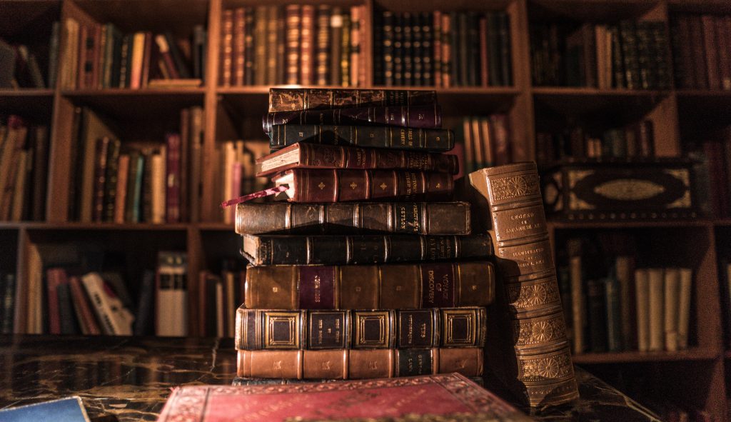 An image of old books, perhaps in a library or archive, with worn covers and faded pages.